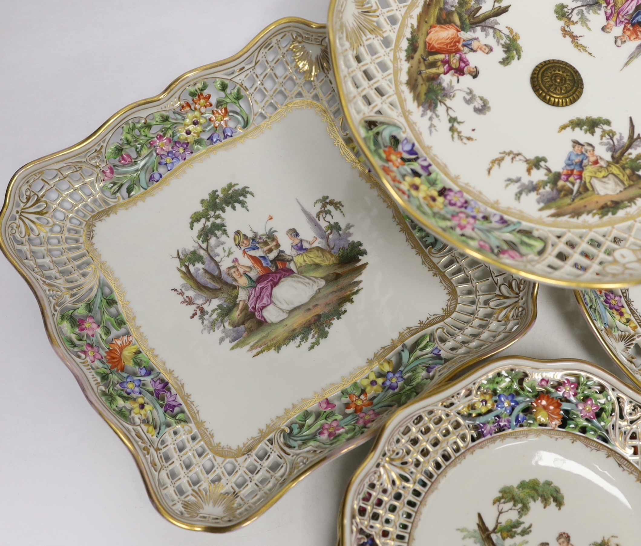 A Dresden Meissen style part dessert set, painted with courting couples in the landscape, consisting of a comport two dishes and four plates, comport 15.5cm high